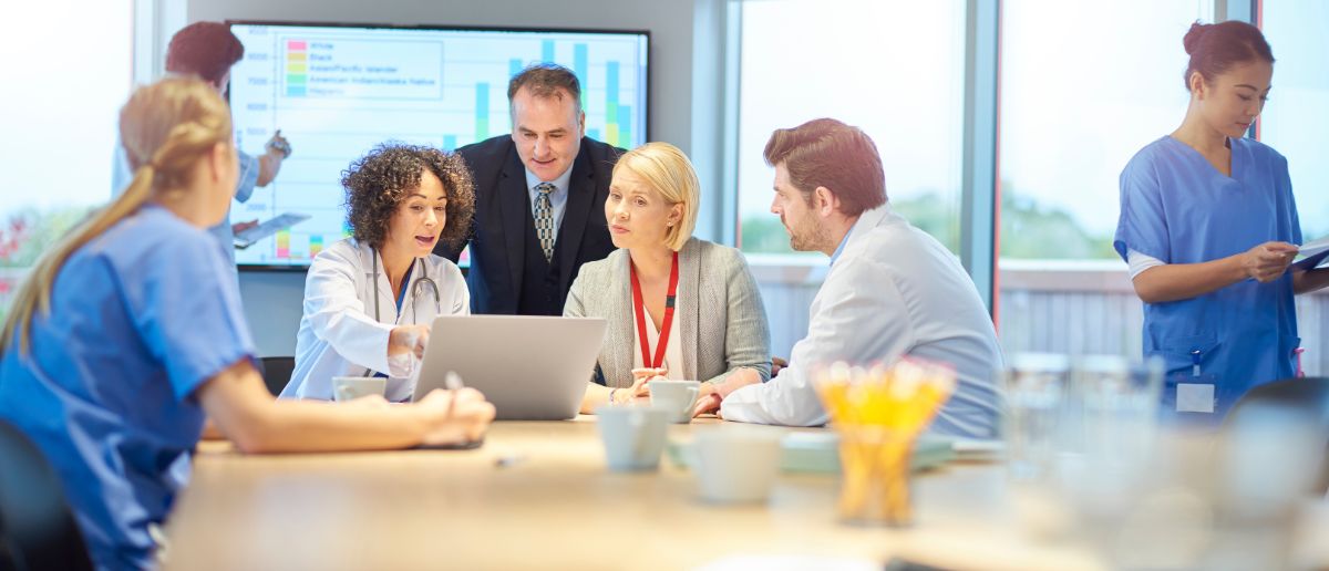 A group of medical professionals discuss a project with their healthcare project manager