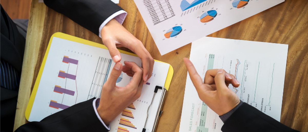 A project coordinator and a project manager comparing their responsibilites on a meeting desk.